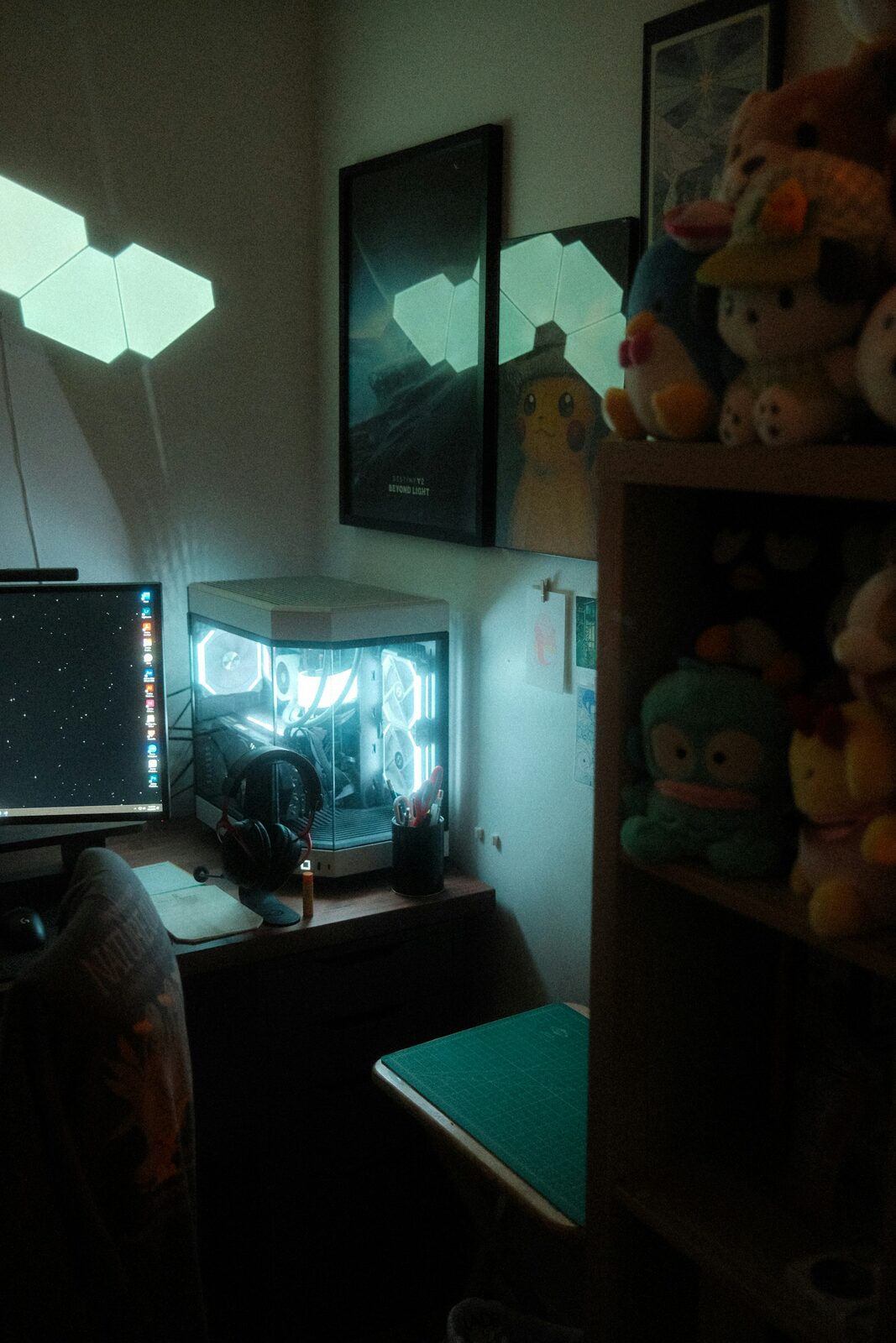 A glowing desktop computer on a desk in a dimly lit bedroom